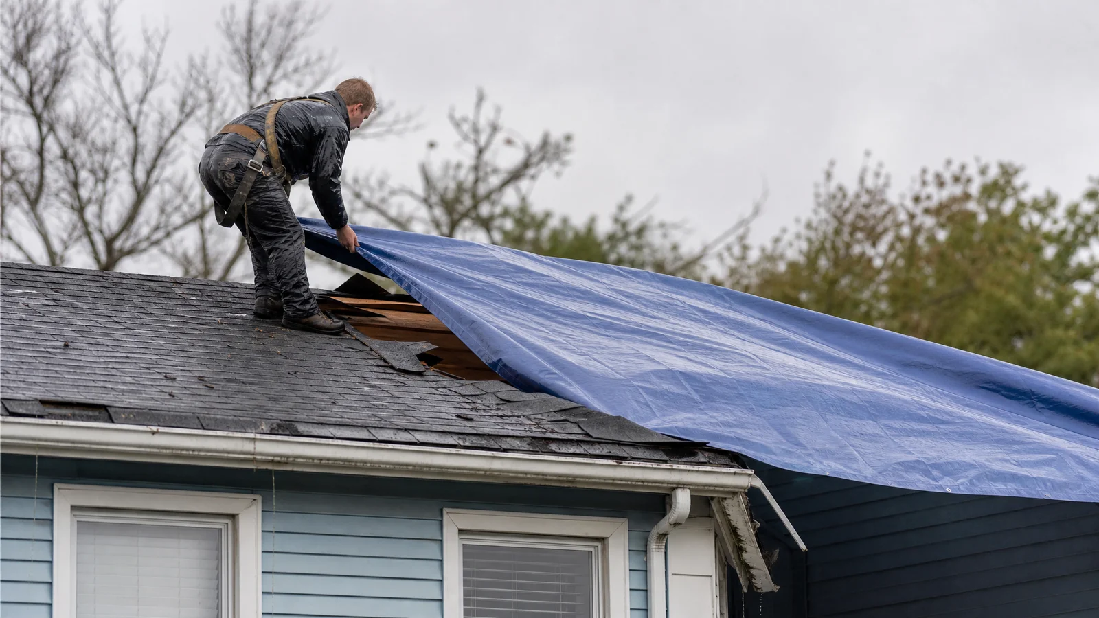 Emergency tarp being installed on storm-damaged roof